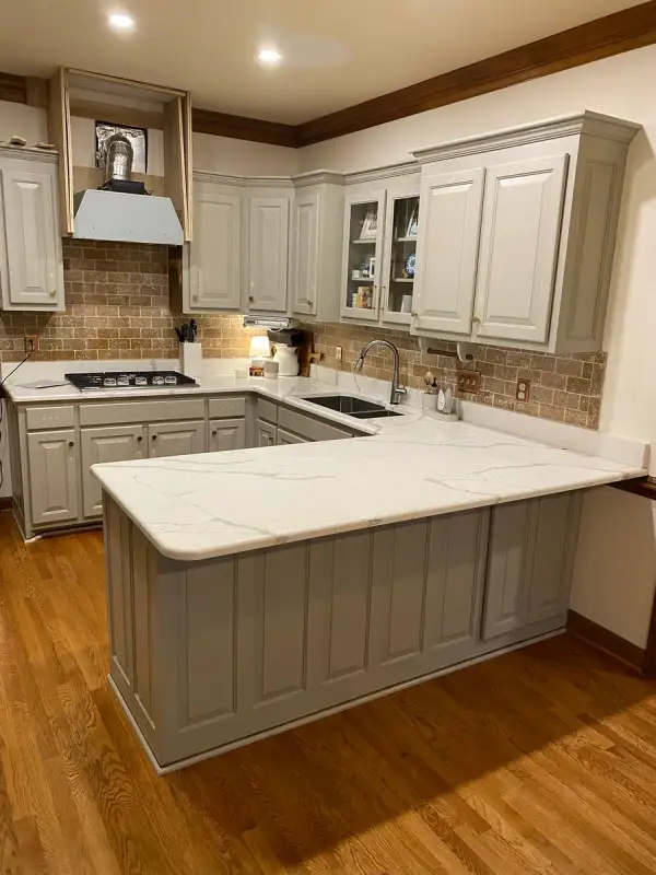 Gray peninsula base and range hood surround in a wood-floored kitchen, Brentwood, TN