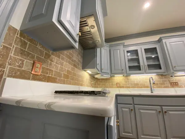 Gray upper cabinets and range hood beside a tile backsplash, Brentwood, TN