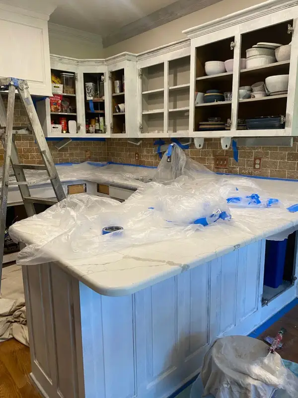 Upper cabinets primed white with doors off, counters under plastic, Brentwood, TN