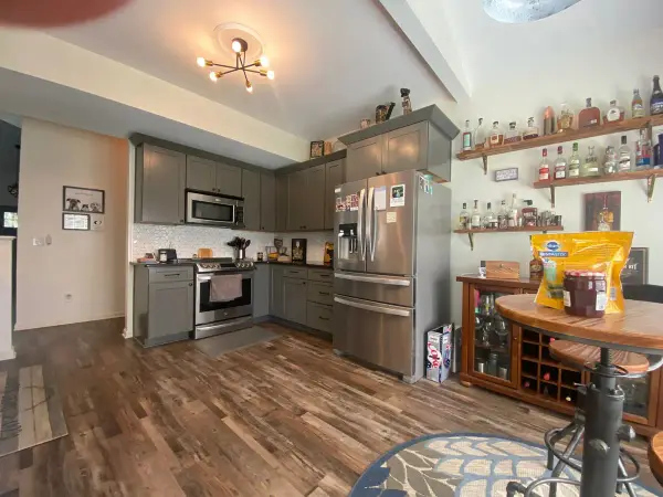 Gray-green kitchen seen across a dining area with plank floors, Franklin, TN