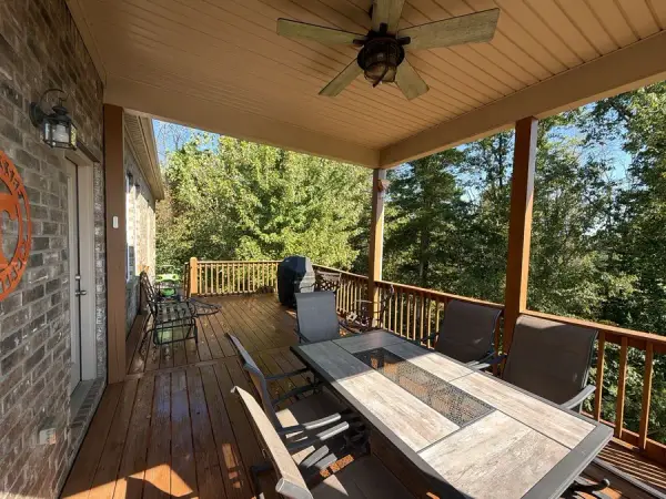 Covered deck under a wood ceiling with fan and dining table, Bellevue, TN