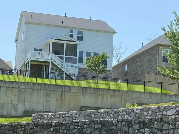 House with white deck railings seen from below a retaining wall, Bellevue, TN