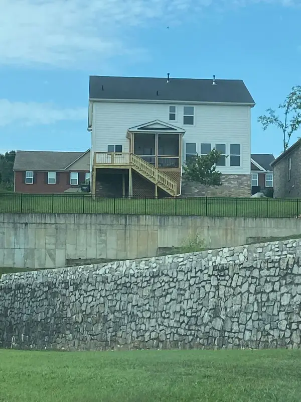 House with deck seen from below a stone retaining wall, Bellevue, TN