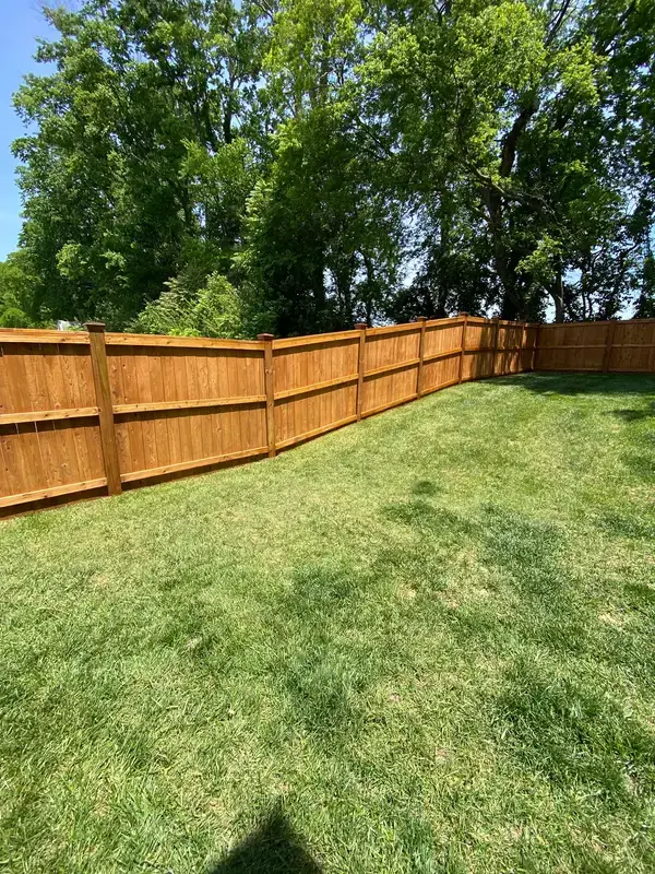 Long cedar-tone privacy fence around a green lawn, Thompson Station, TN