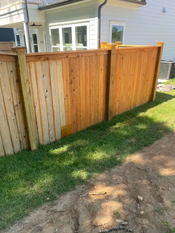 Privacy fence section mid-stain behind a new house, Thompson Station, TN