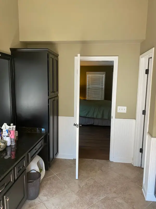 Tan hall with white wainscoting beside a black cabinet, Bellevue, TN