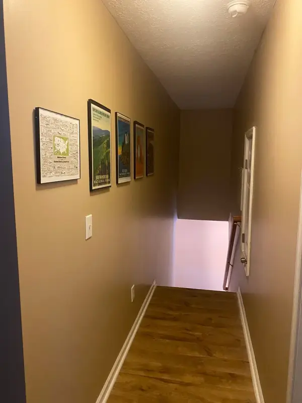 Tan-walled hall with framed prints leading to stairs down, Bellevue, TN