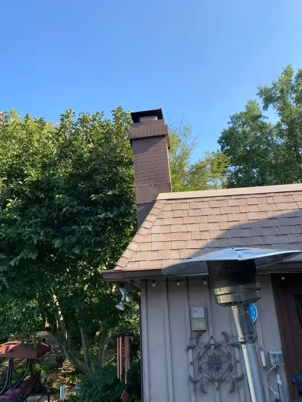Gray vertical siding and brick chimney under trees, Franklin, TN