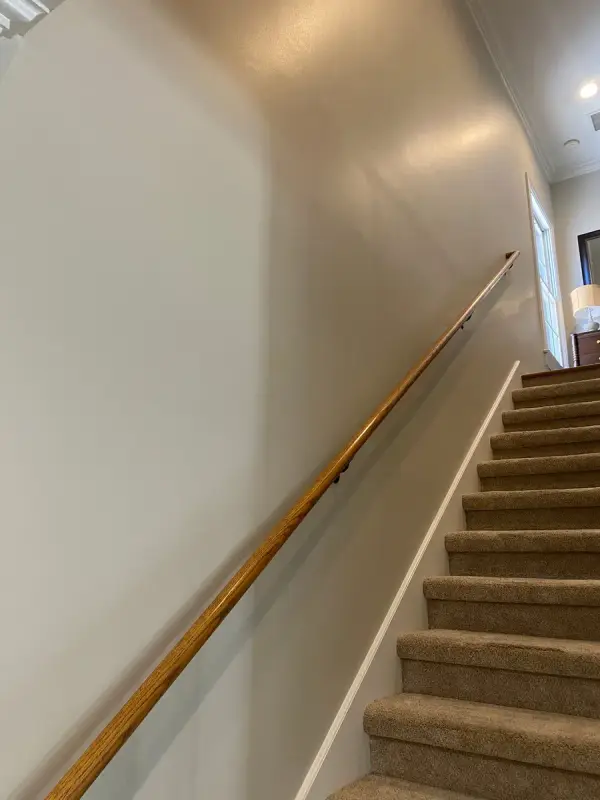 Carpeted stair with oak handrail along a greige wall, Brentwood, TN