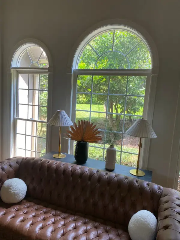 Two arched windows with white trim behind a leather sofa, Franklin, TN