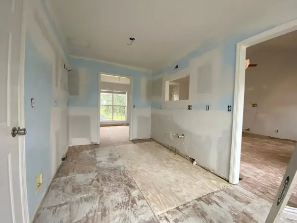 Long room with patched blue walls and bare subfloor, Pleasant View, TN