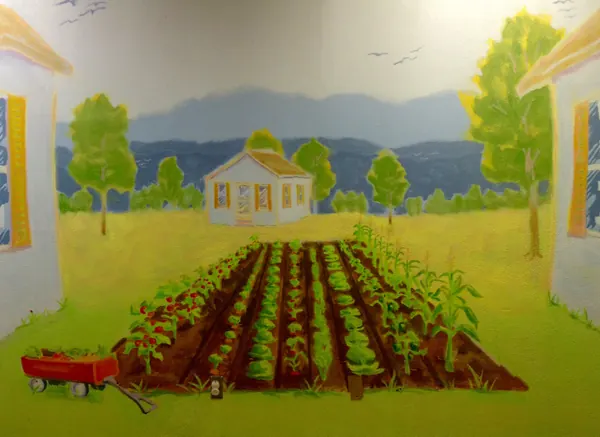 A mural of a vegetable garden, a white house, blue hills and a red wagon, by Alan Robinson
