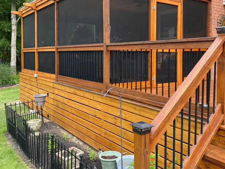 Cedar-stained screened porch and stair with black balusters above a garden bed, part of the deck staining we do for Franklin homes