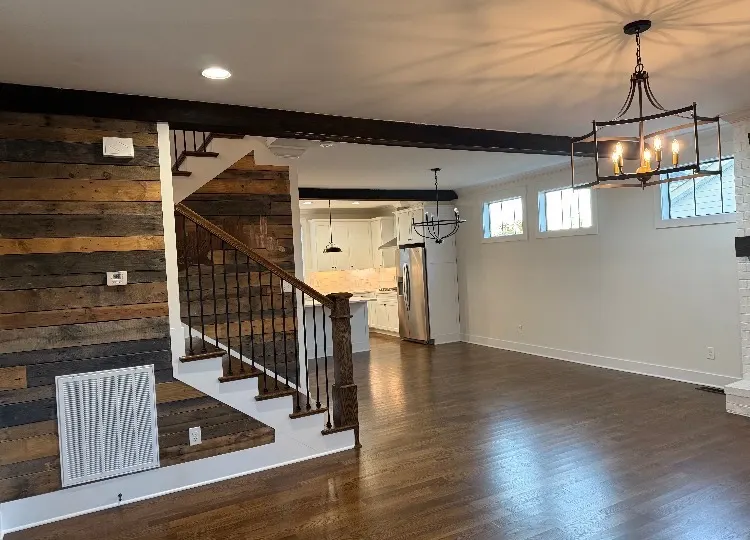 Open living area with a reclaimed-wood accent wall, a staircase and fresh white paint, part of the interior painting we do for Franklin homes