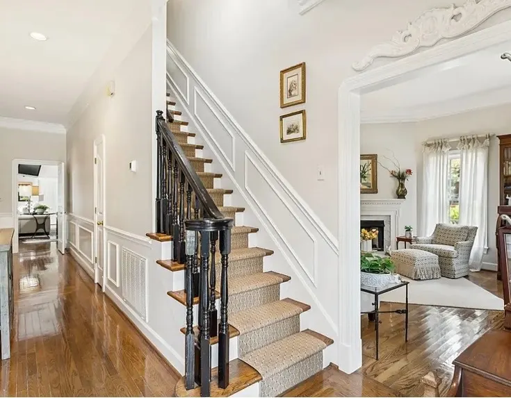 Staircase with detailed wainscoting and crown molding painted crisp white, part of the interior painting we do for Belle Meade homes