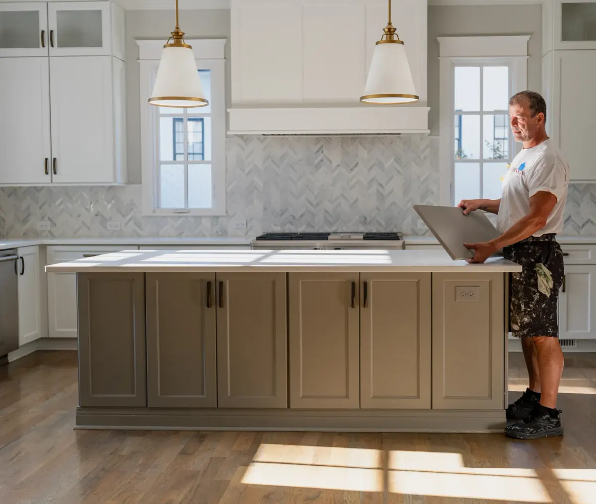 Alan Robinson setting a freshly finished cabinet door on a kitchen island, part of the Robinson family business serving Bellevue