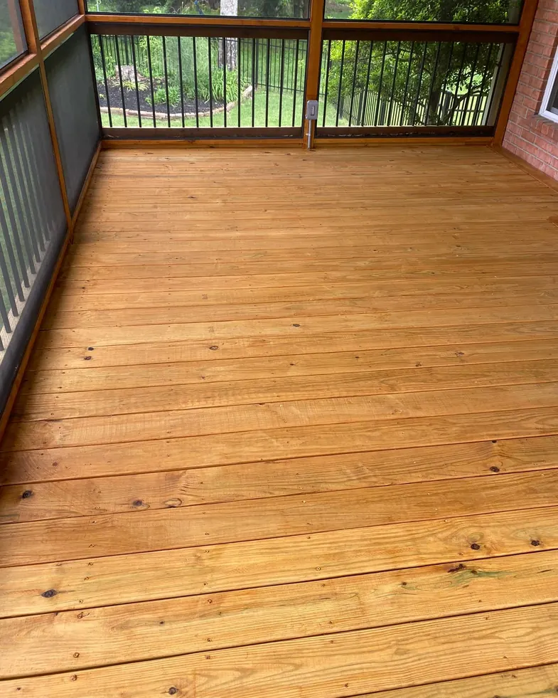 Freshly stained deck boards inside a screened porch with black balusters, one of our deck staining projects for Bellevue homes