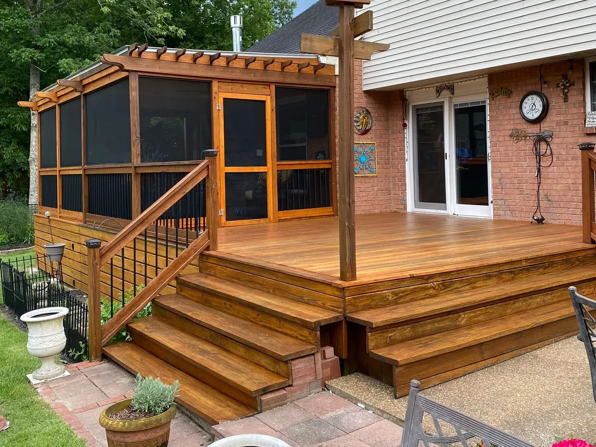 Cedar-stained deck with wide steps and black balusters beside a screened porch, one of our deck staining projects for Bellevue homes