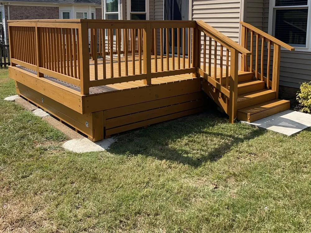 Honey-stained deck with square balusters and a short stair down to a concrete pad, part of the deck staining we do for Bellevue homes