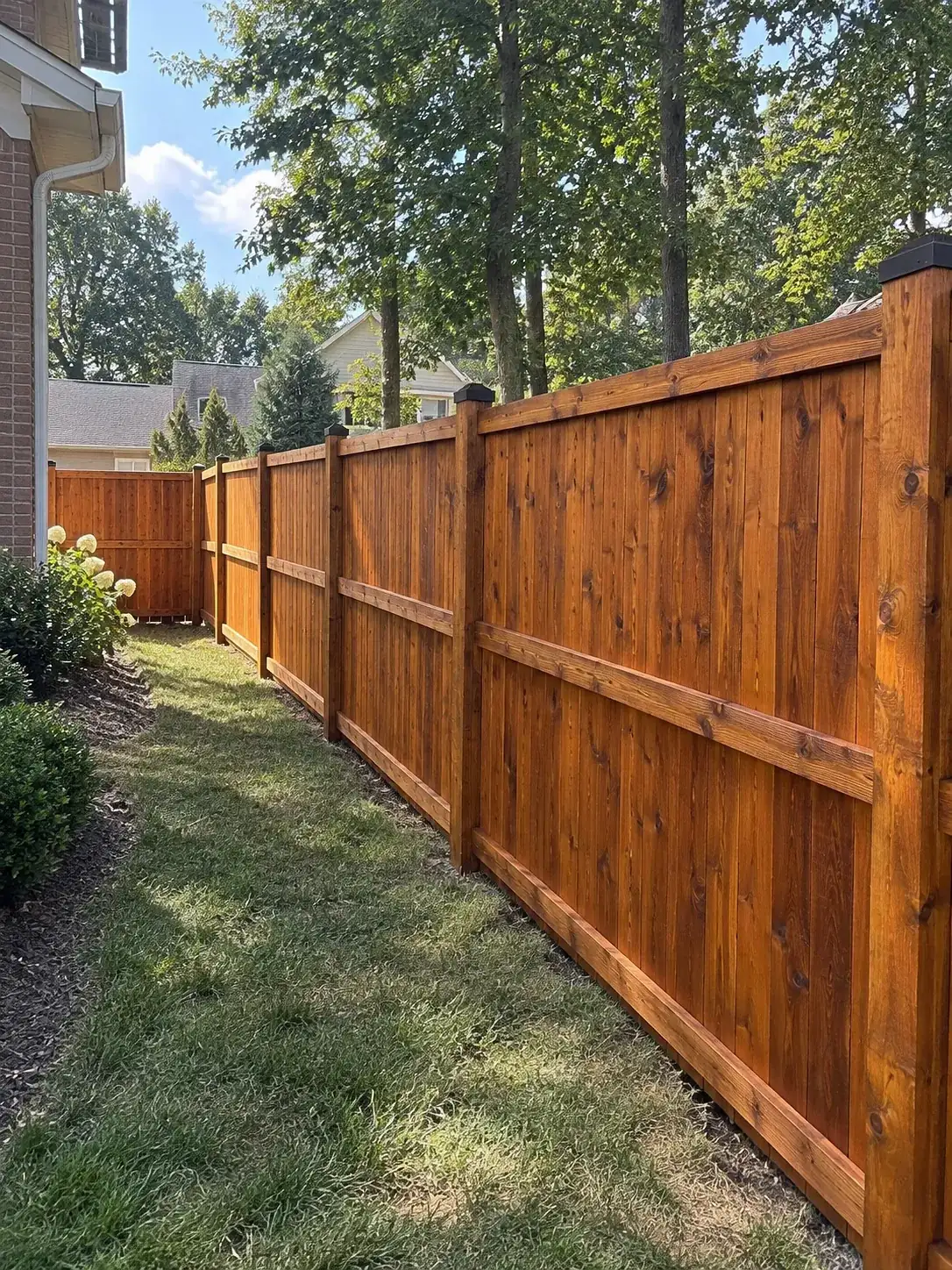 Tall cedar privacy fence with dark post caps, stained a rich warm tone, fence staining for Belle Meade homes