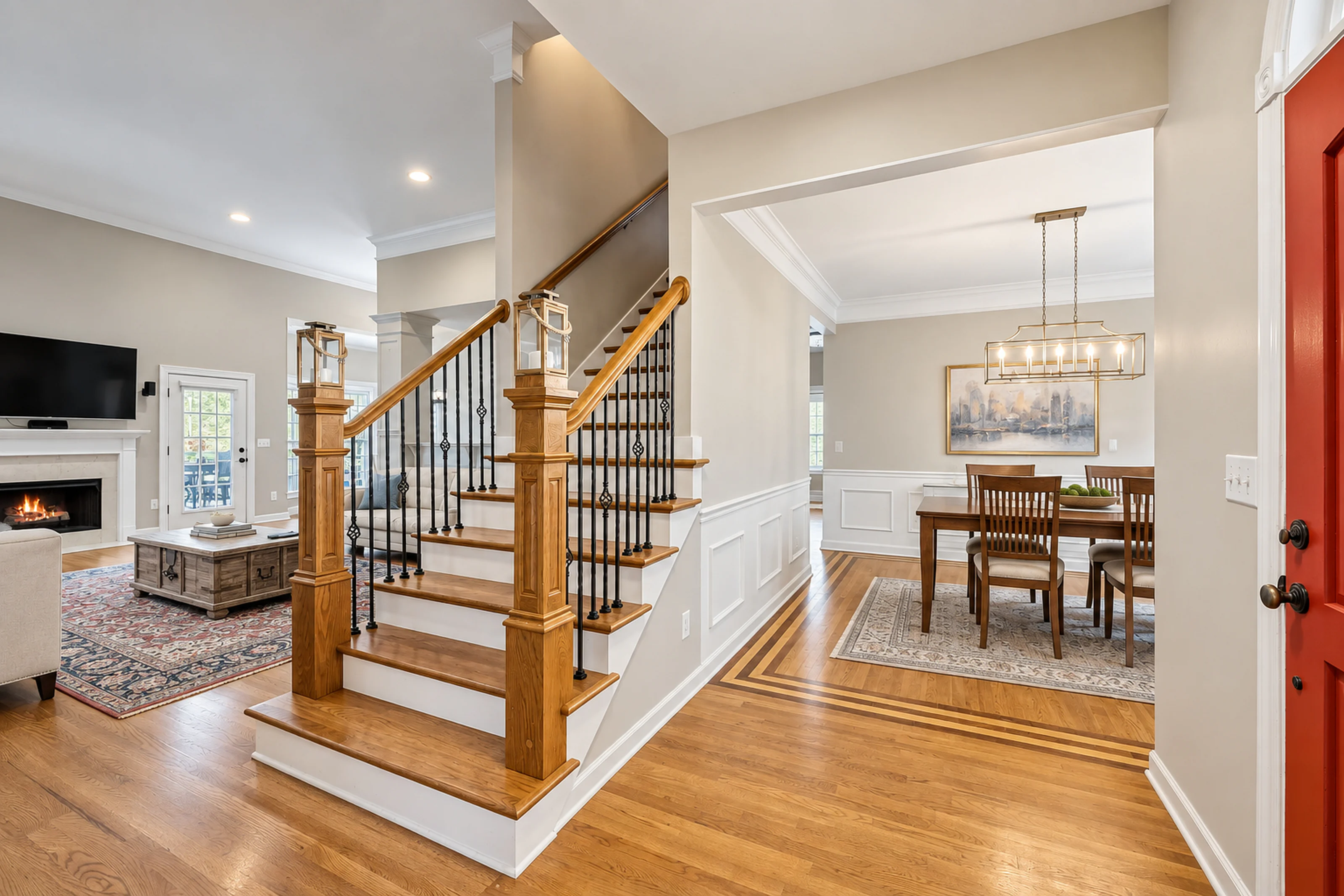 Illustrative foyer staircase with iron balusters and white painted wainscoting opening to a dining room, interior painting for Brentwood homes