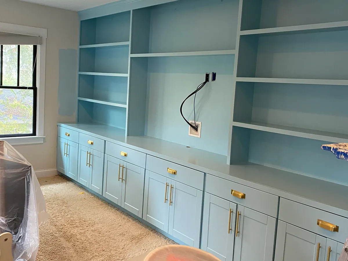 Built-in cabinetry mid-project, pale blue doors freshly painted and the room under sheeting, a step in our cabinet painting process for Bellevue homes
