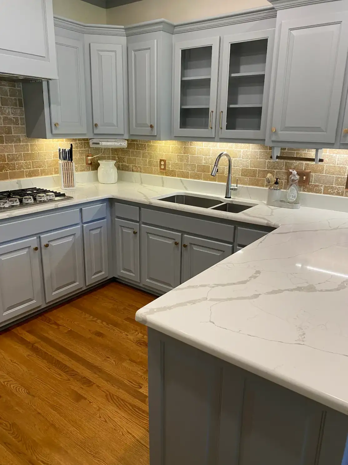 Abigail W.'s gray-painted cabinets with glass-front uppers, a customer photo from a Google review