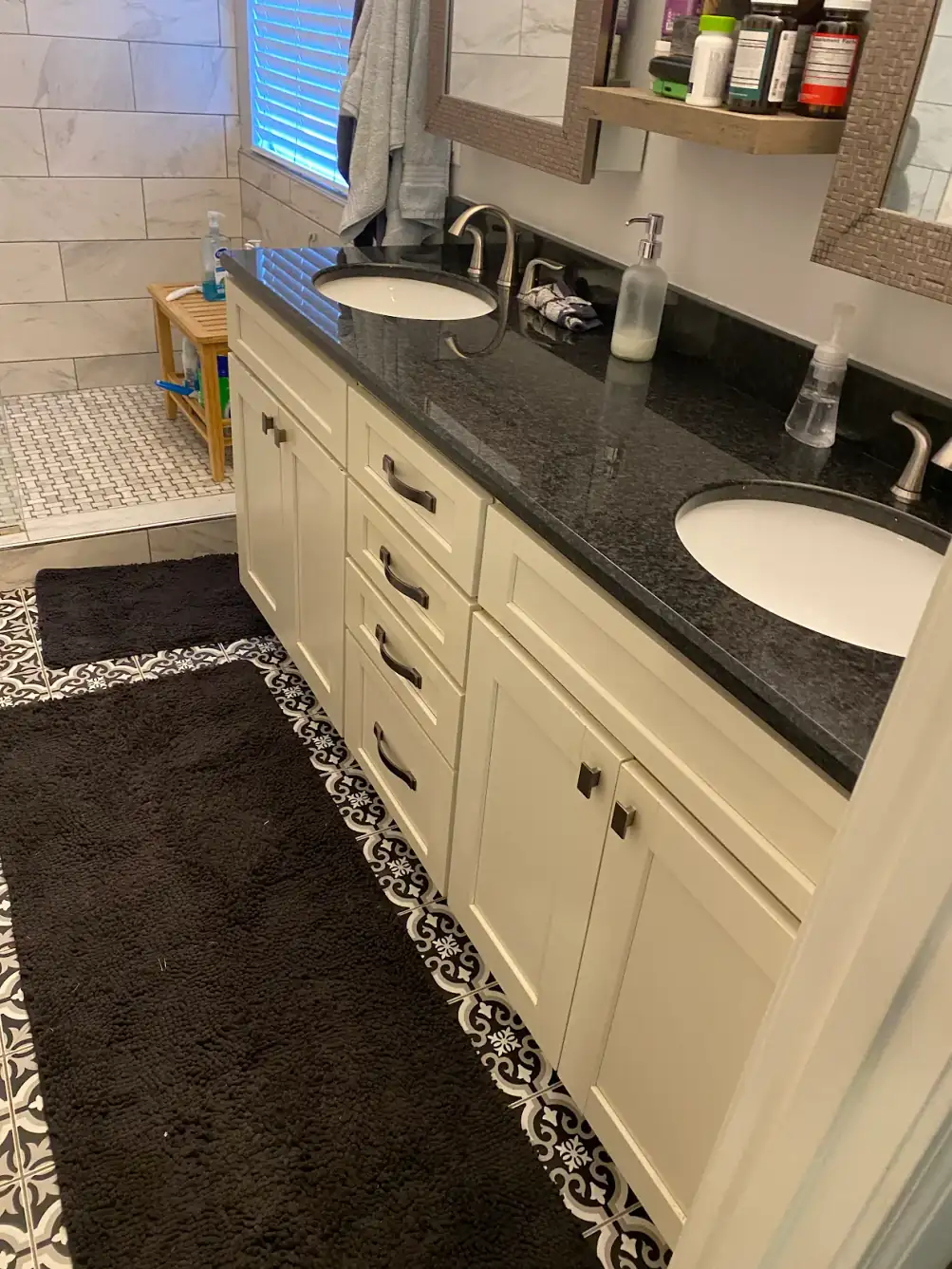 Barbara K.'s cream bathroom vanity under a black granite top, before painting, a customer photo from a Google review